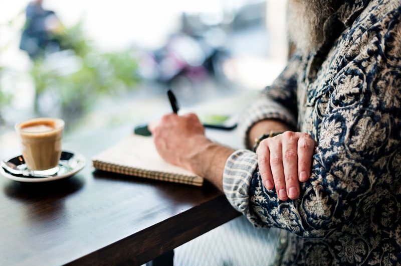 hombre escribiendo con cafe