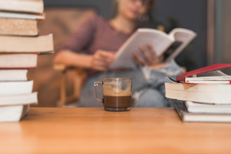 mujer leyendo con café entre libros